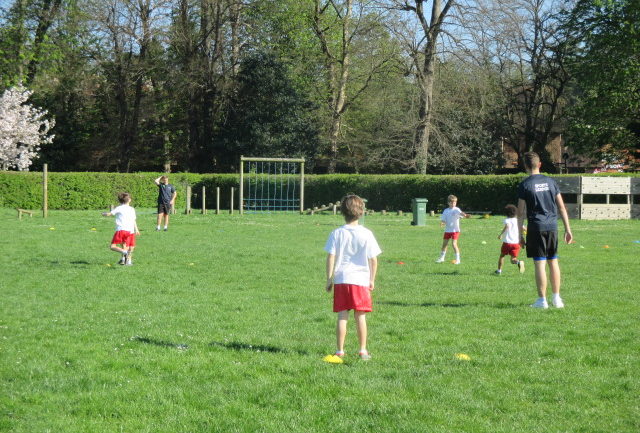 School children running on field with student instructors