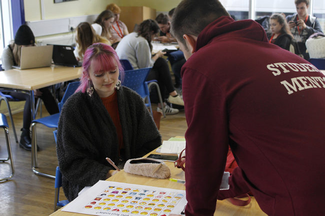 Student mentor showing student a feelings chart