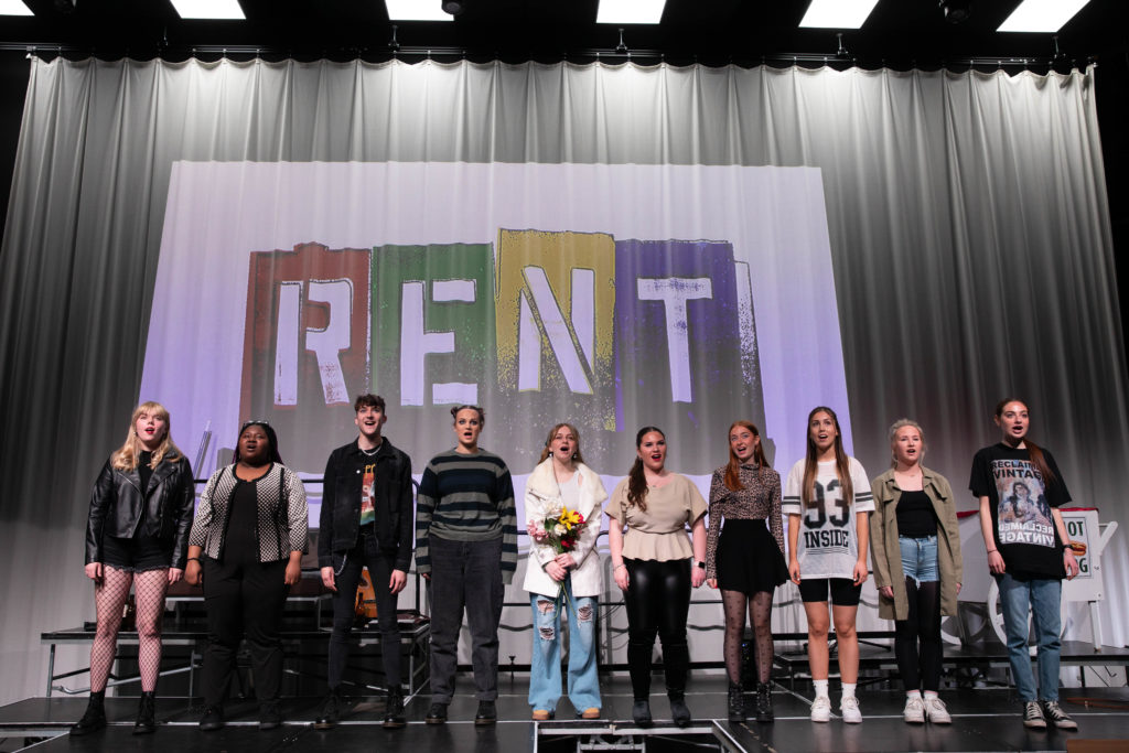 Group photo of ten students singing on stage.