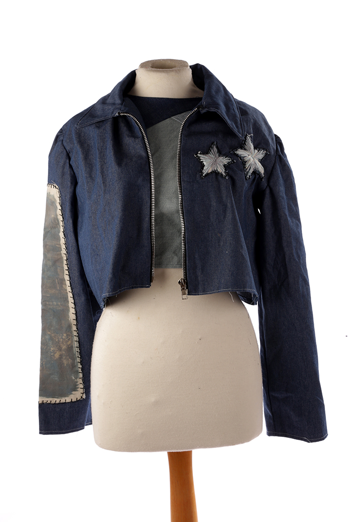 Front of denim jacket over a top, with star design on one side of jacket