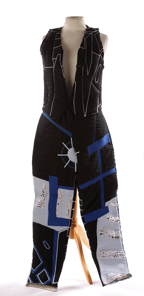 Black waistcoat with a white stitched pattern, and black trousers with blue design on mannequin