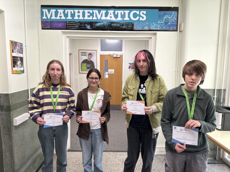 The four students who took part in the Maths Olympiad for girls, standing in the Mathematics building holding their certificates.