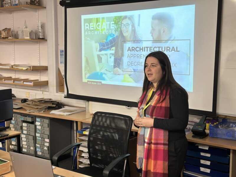 Lauren delivering her talk to students, standing in front of a screen displaying the presentation