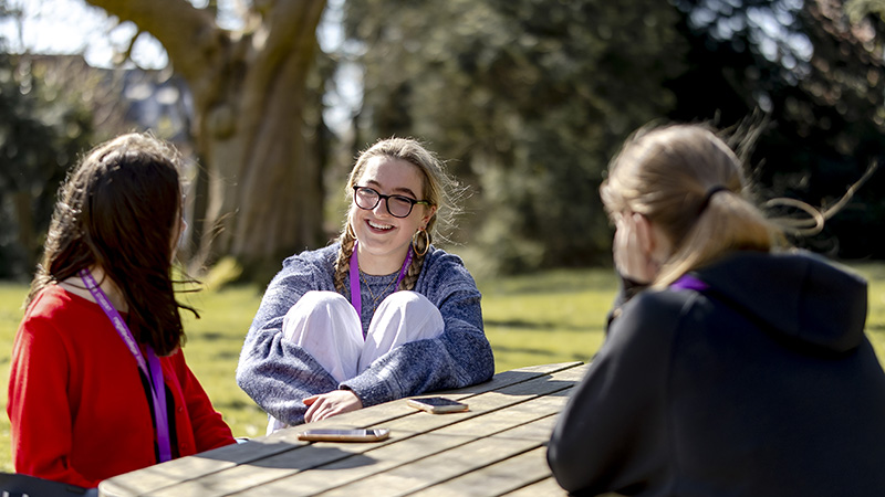 Three female students talking in the College grounds