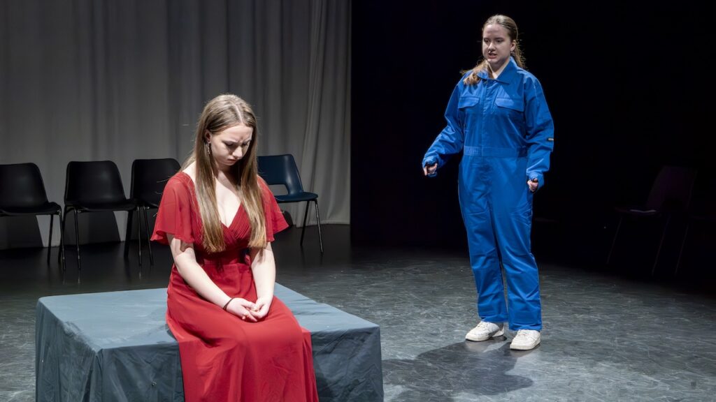Students on stage performing Antigone in modern costumes
