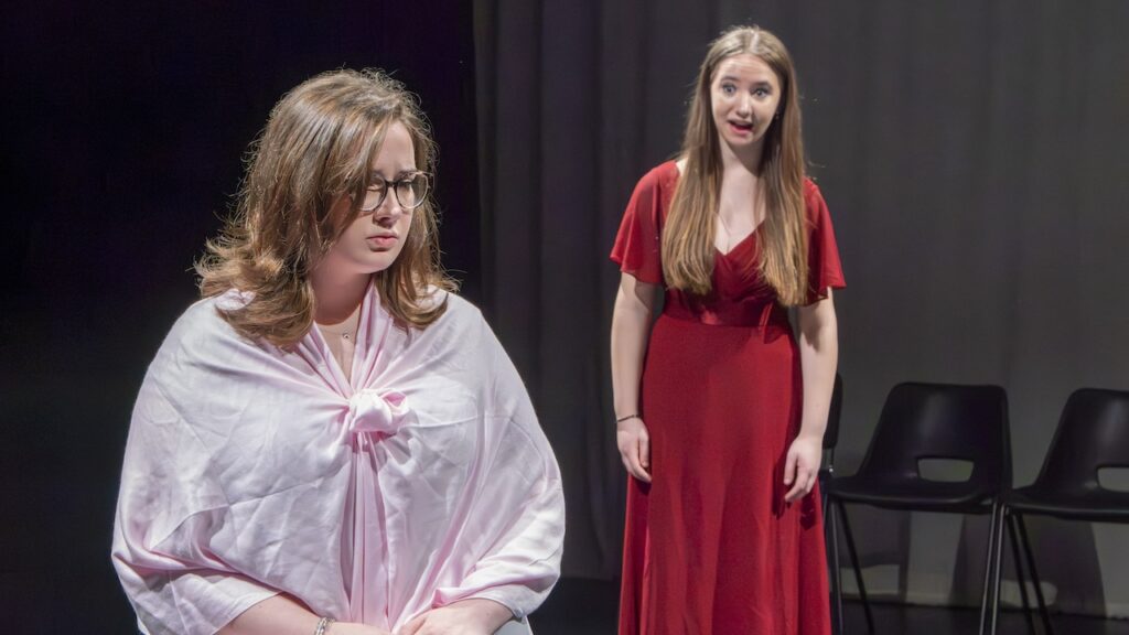 Students on stage performing Antigone in modern costumes