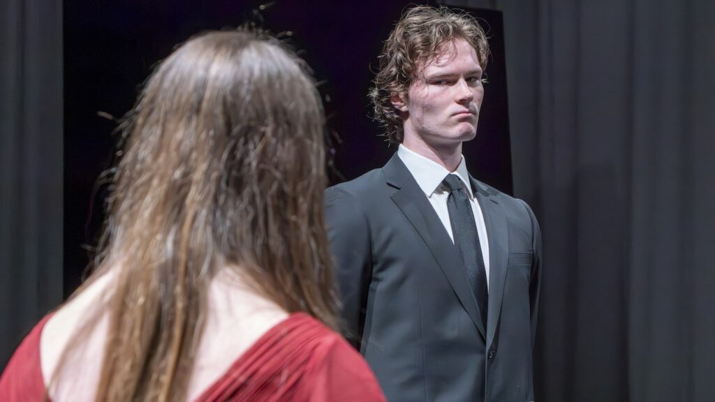 Students on stage performing Antigone in modern costumes
