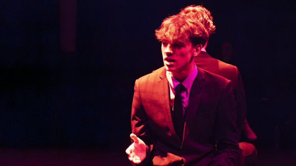 Students on stage performing Antigone in modern costumes