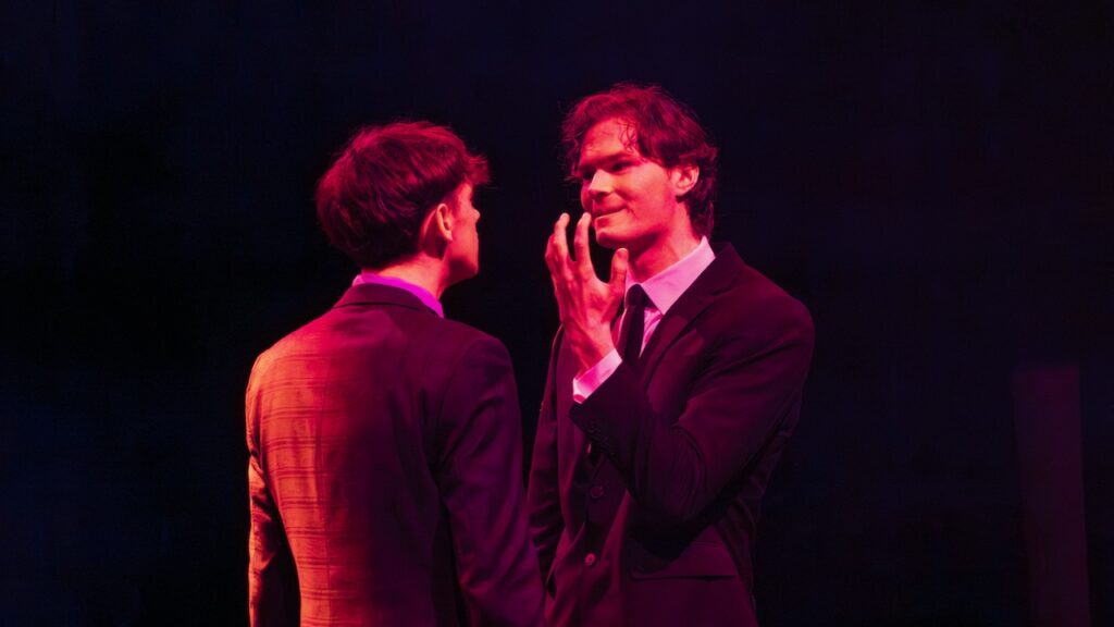 Students on stage performing Antigone in modern costumes