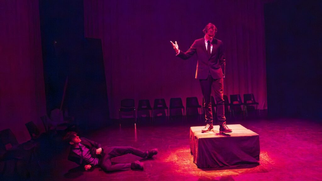 Students on stage performing Antigone in modern costumes