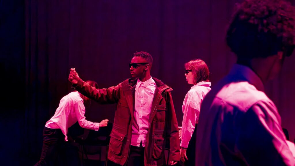Students on stage performing Antigone in modern costumes