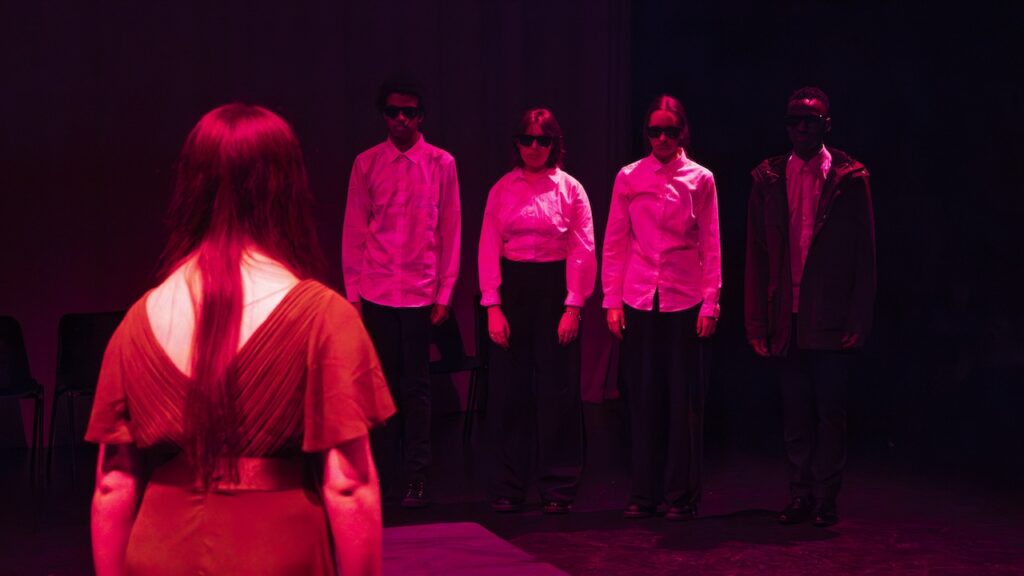Students on stage performing Antigone in modern costumes