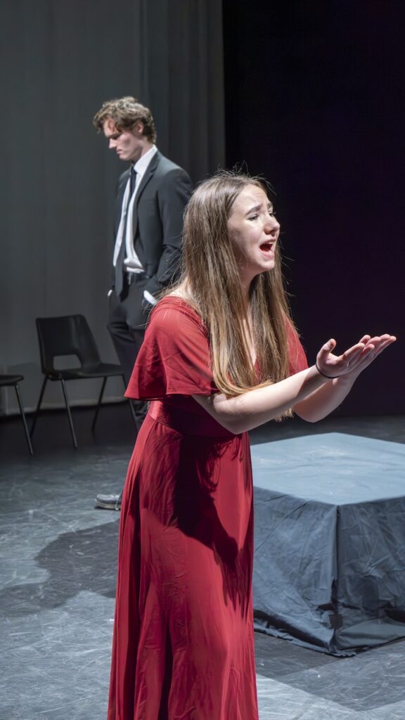 Students on stage performing Antigone in modern costumes