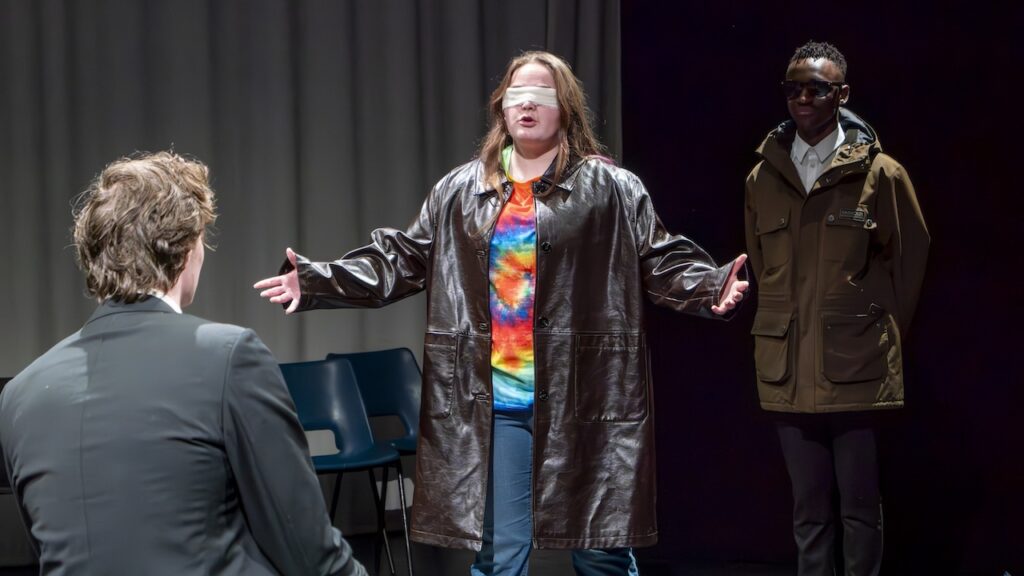 Students on stage performing Antigone in modern costumes