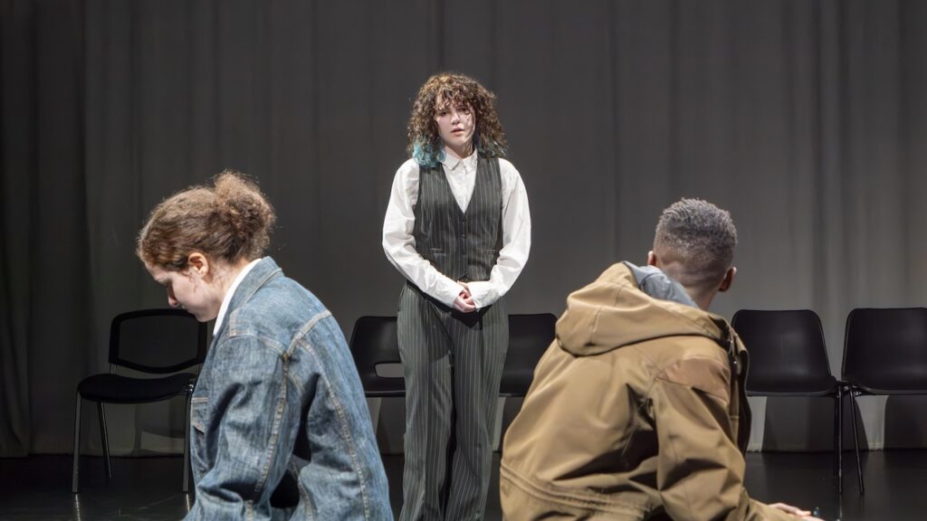Students on stage performing Antigone in modern costumes