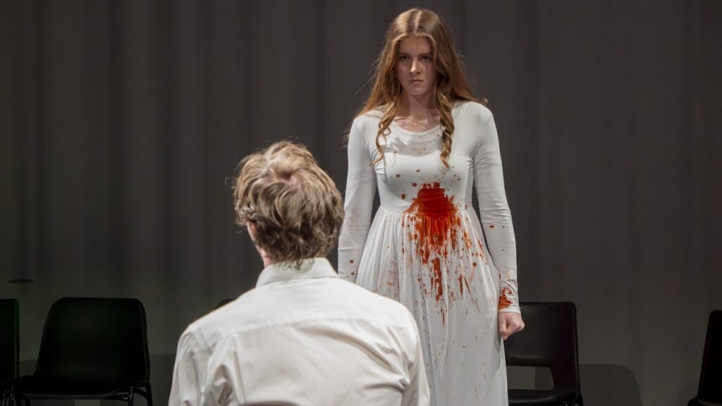 Students on stage performing Antigone in modern costumes