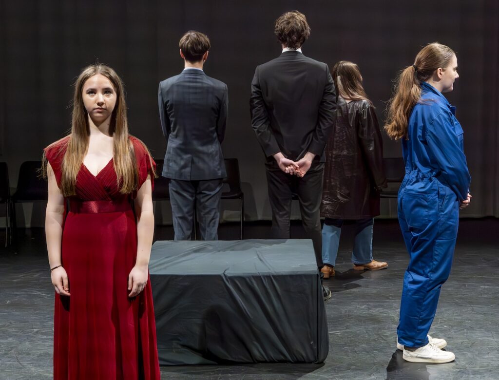 Students on stage performing Antigone in modern costumes