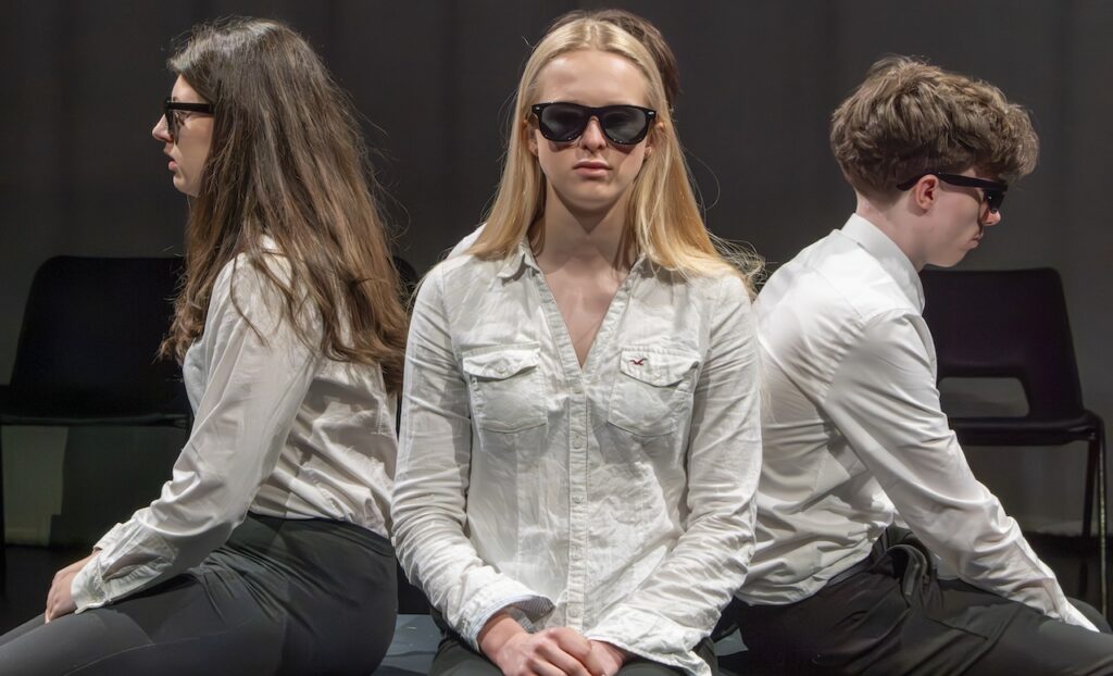 Students on stage performing Antigone in modern costumes