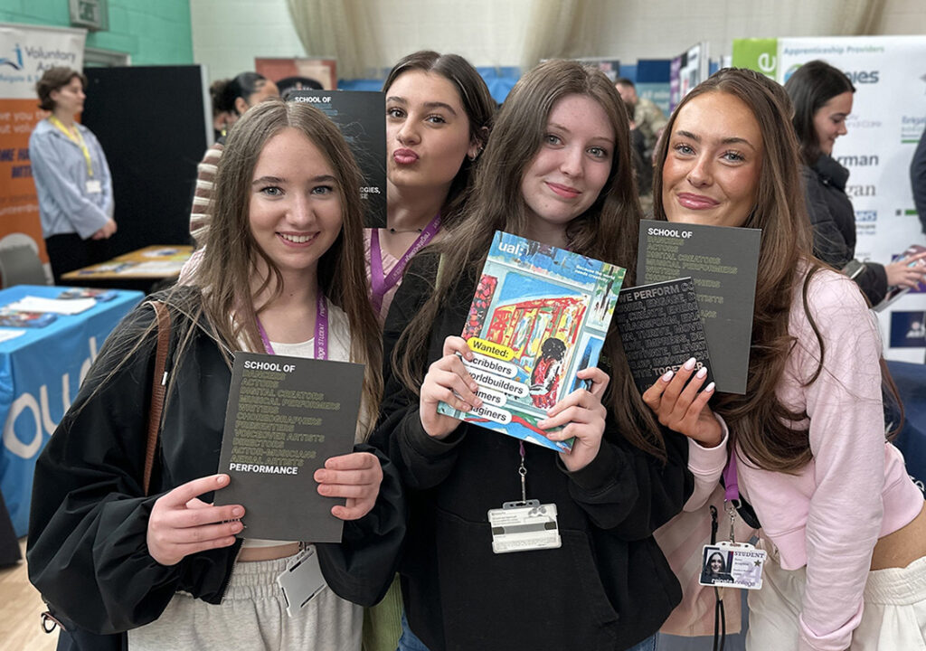 Four female students posing with higher education brochures