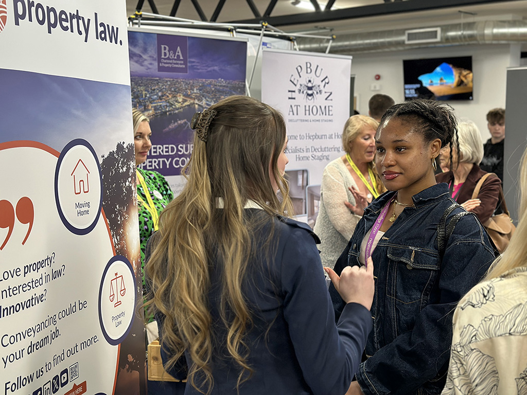 A female student speaking to an exhibitor at the Meet the Employer event