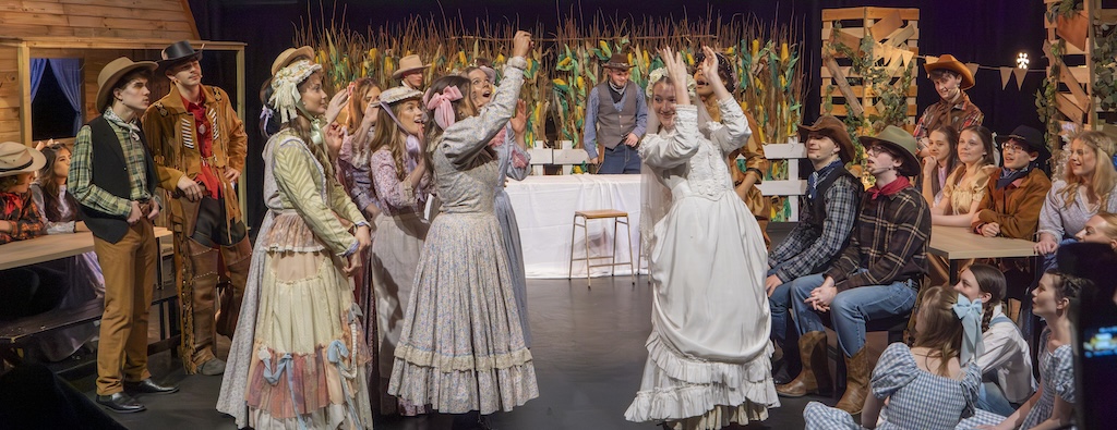 Students performing on stage in the production of Oklahoma - Curley and Laurie's wedding