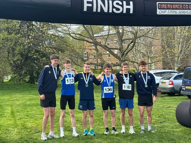 6 runners wearing their kit lined up at the finish line