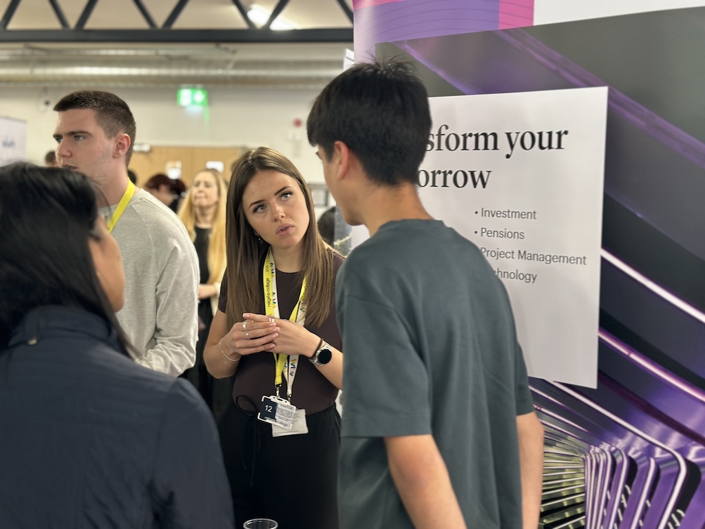 An employer speaking to students and their parents on their stand at the Meet the Employer event