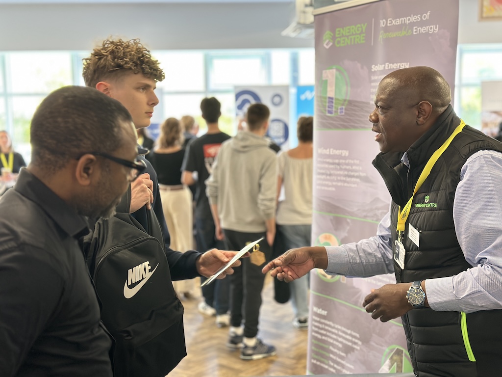 An employer speaking to students and their parents on their stand at the Meet the Employer event