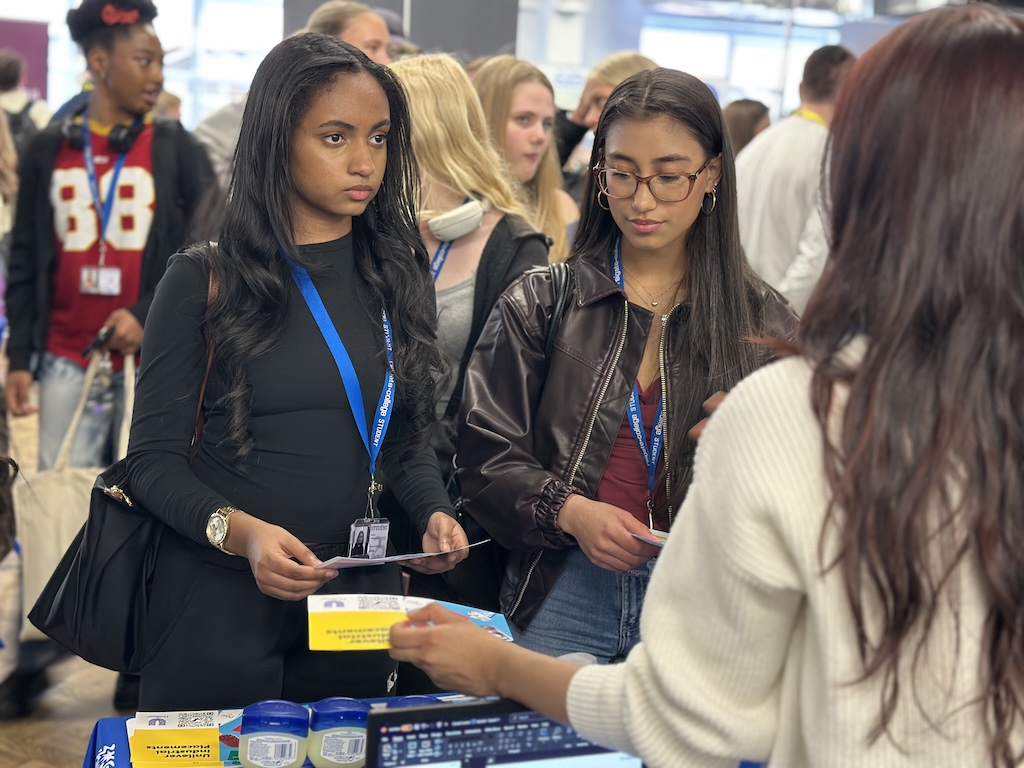 An employer speaking to students and their parents on their stand at the Meet the Employer event
