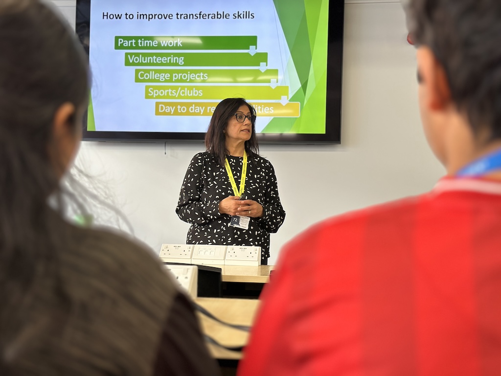 Guest speaker presenting to student audience, standing in front of PowerPoint presentation on screen