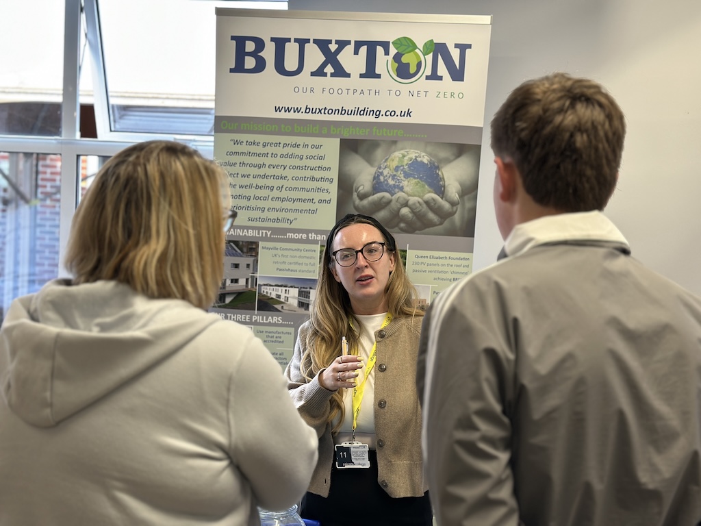 An employer speaking to students and their parents on the Buxton stand at the Meet the Employer event