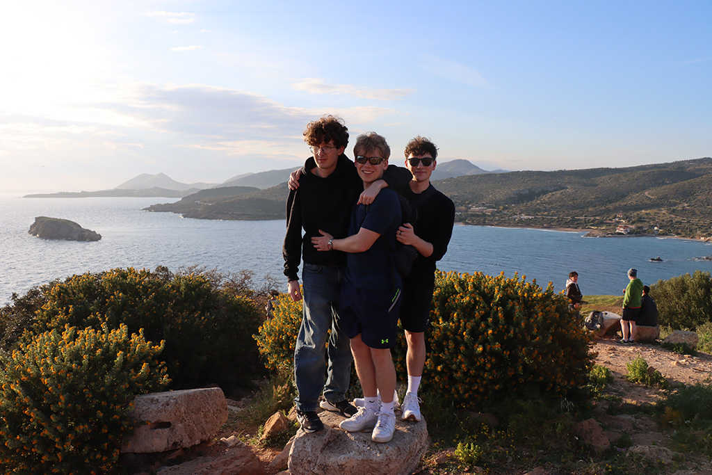 Three students standing on a rock at Cape Sounion