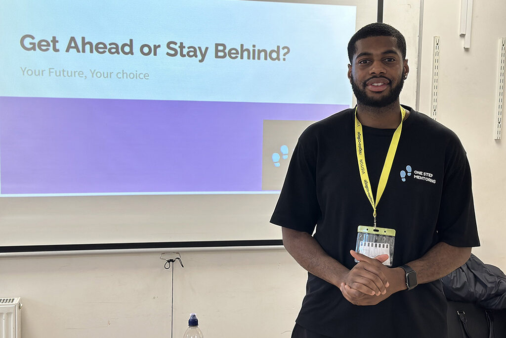 Guest speaker in front of his presentation with the title "Get Ahead or Stay Behind" on the screen.
