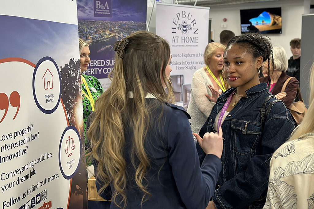 A female student speaking to an exhibitor at the Meet the Employer event